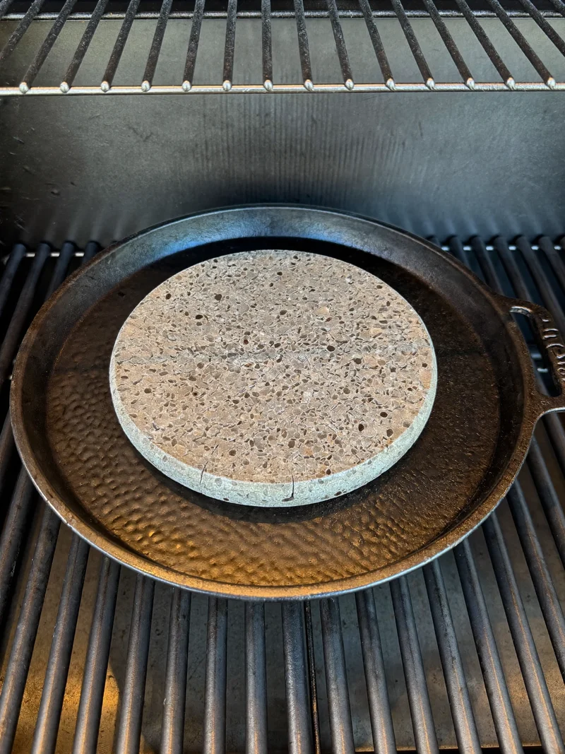 Plită din fontă și piatră pentru pizza așezate pe o grilă fierbinte
